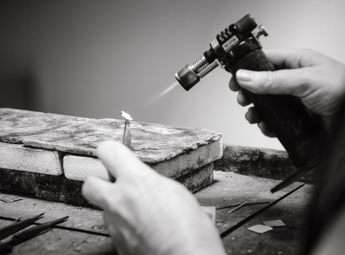 hands using a blowtorch to solder