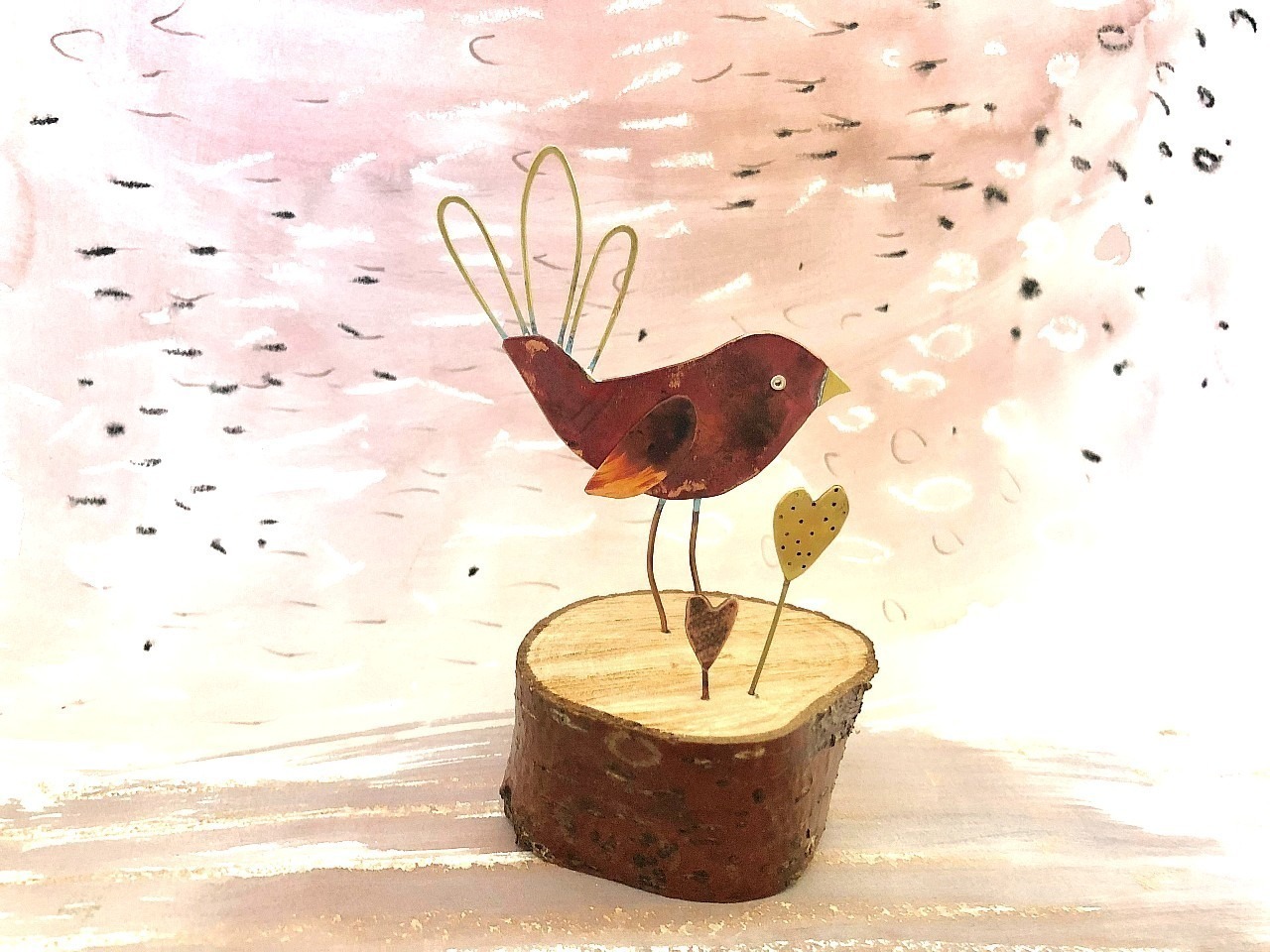 a red copper bird on a piece of wood